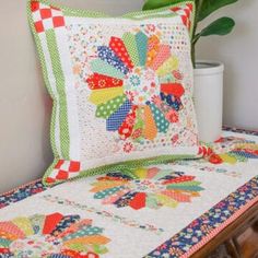 a quilted pillow sitting on top of a bed next to a potted plant