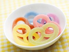 a bowl filled with different colored rings on top of a yellow and white table cloth