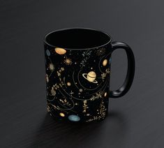 a black coffee mug with planets and stars on it