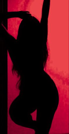 the silhouette of a woman is shown in front of a red wall with her arms up