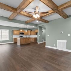 an empty living room with wood floors and ceiling fan in the middle of the room