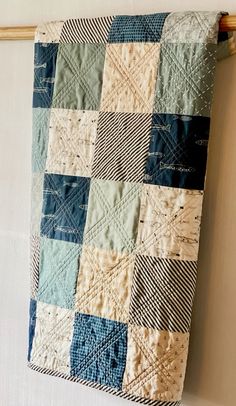 a blue and white quilt hanging on a wall next to a wooden hook with clothes pins in it