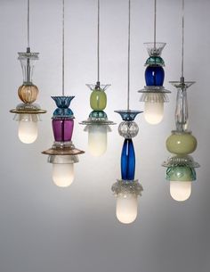 a bunch of different colored vases hanging from a light fixture with lights attached to them