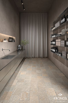 an empty room with shelves filled with bottles on the wall and a sink in the middle