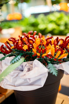 an arrangement of orange and red flowers in a pot