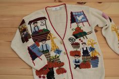 a white sweater with pictures on it sitting on a wooden floor