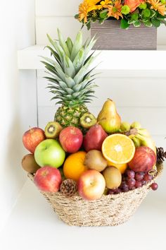 a basket filled with fruit sitting on top of a white counter next to a potted plant