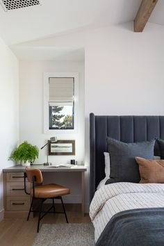 a bedroom with a bed, desk and chair next to a window in the corner