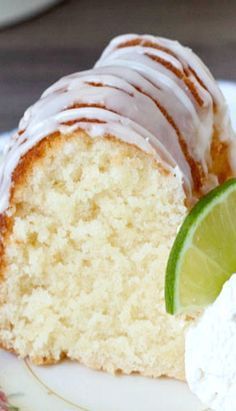 a piece of cake with frosting and a lime slice on the plate next to it