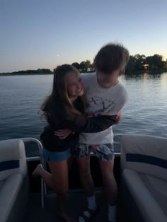 two young people hugging on the back of a boat