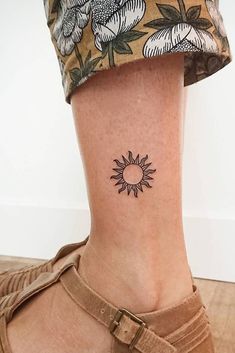 a woman's foot with a small sunflower tattoo on her left side ankle