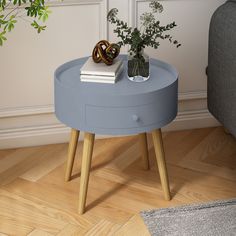 a small blue table with a plant on top and a book sitting on the end