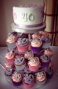 a tiered cake with pink and purple cupcakes