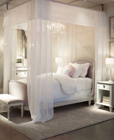 a bedroom with a white canopy bed and chandelier