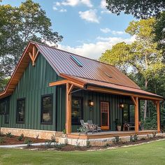 a green house with a metal roof and wooden trim on the front, surrounded by trees