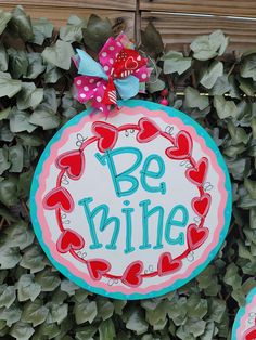 a sign that says be mine hanging from the side of a wall covered in green leaves