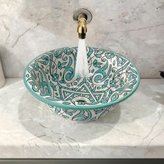 a blue and white bowl sink sitting on top of a counter next to a faucet