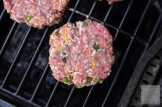 three hamburger patties cooking on a grill with cheese and green onion sprinkles