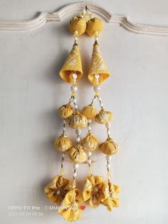 a yellow and white wall hanging with bells on it's side next to a window