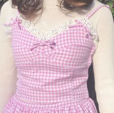 a woman wearing a pink gingham dress with white lace on the neckline