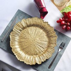 a gold plate sitting on top of a table next to silverware and red berries