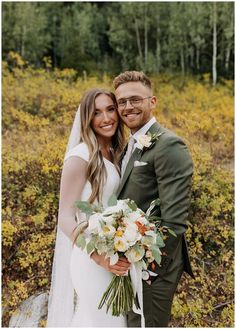 a bride and groom pose for a photo in front of the woods on their wedding day