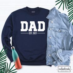 Dad Est 2021 Sweatshirt, Custom Dad Sweatshirt, Custom Date Sweatshirt, Dada Sweatshirt, Personalized Father Shirt, Est Date Dad Shirt. Hi! Welcome to our store. It's good to see you here. IMPORTANT MATTERS FOR ORDERING: 1-) Please check and review all photos. 2-) Our sizes are true to size, but can you take a look at my measurements in the product details section to make sure you get the best fit? The measurement is from armpit to armpit. Please let me know if you have any questions. BUSINESS D White Long Sleeve T-shirt For Father's Day, Father's Day Long Sleeve Letter Print T-shirt, Father's Day Long Sleeve T-shirt With Letter Print, Long Sleeve T-shirt With Letter Print For Father's Day, Father's Day Long Sleeve Relaxed Fit Sweatshirt, Father's Day Casual Sweatshirt With Name Print, Father's Day Long Sleeve T-shirt With Name Print, Blue Crew Neck Sweatshirt With Name Print, Father's Day Casual Graphic Sweatshirt