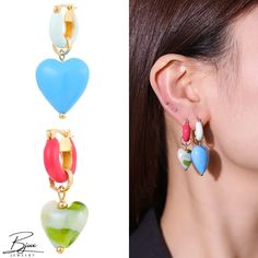 a woman wearing three different colored heart shaped earrings