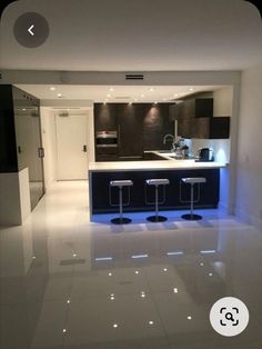 an empty kitchen with bar stools in the center and white floor tiles on the walls