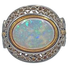 Handmade opal ring in platinum and 18k yellow gold by New York jewelry designer Judy Geib. Central cabochon cut 12 x 9mm pinfire opal, horizontally set in an 18 karat yellow gold bezel. The opal has a vibrant green, blue, and orange play of color. Platinum open-work scroll design surrounds the opal, with a matching open-work band having geometric gold dotted centers. Unsigned. Originally sold by Greenleaf & Crosby in 2015. Finger size 6. Judy Geib, is a NYC based designer who creates hand made pieces with a Bohemian elegance. Her pieces are uniquely one of a kind and usually takes form as it’s made, rather than being designed in advance. Judy Geib, Yellow Gold Opal Ring, Gold Opal Ring, Gold Vans, New York Jewelry, Australian Black Opal, Trio Ring, Carnelian Ring, Opal Ring Gold