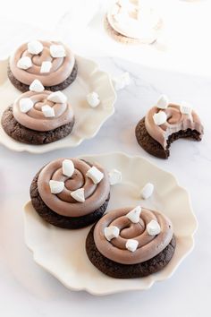 three cookies with marshmallows on them sitting on plates