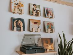 a record player sitting on top of a wooden shelf next to a potted plant