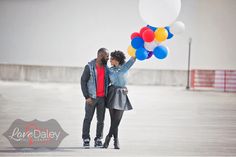 a man and woman are holding balloons in the middle of an empty parking lot,