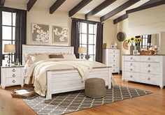 a white bed sitting on top of a wooden floor next to a dresser and mirror