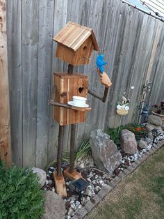 a bird house made out of wood with a cup on it's top and a spoon in its mouth