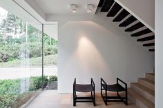 two chairs sitting on the floor in front of a stair case with glass walls and wooden steps