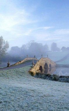 a foggy field with an old bridge in the distance