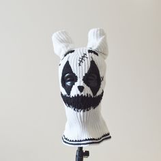 a white and black knitted panda bear hat on a tripod with a camera