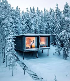 an image of a cabin in the snow with trees and stairs leading up to it