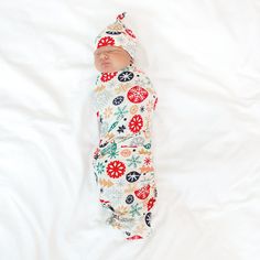 Top view image of baby laying down while wrapped in the Modern & Merry Swaddle & Hat Set Family Holiday Cards, Neutral Background, Peppermint Mocha, Holiday Baby, Baby Gown, Box Making, Nightgowns For Women, Santa Sleigh, Hat Set