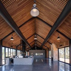 a large open room with high ceilings and wooden beams on the ceiling is lit by pendant lights