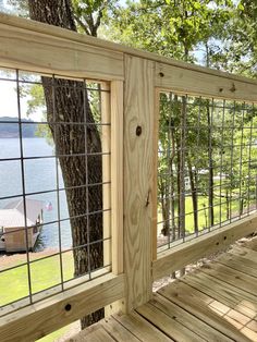 a wooden deck with metal railings next to a tree and lake in the background