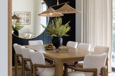 a dining room table with white chairs and a large mirror hanging over it's head