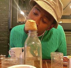 a man sitting at a table with a bottle and food in front of him on his face