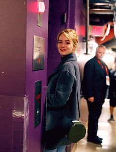 a woman standing next to a purple wall