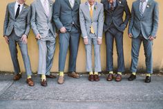 a group of men standing next to each other wearing suits and ties with yellow socks