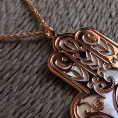 "Hamsa in rose gold on 925 silver and mother of pearl backdrop. In the symbol it is shown Fatima's palm-shaped whose meaning is \"five\". Also named Hand of Miriam, Hamsa or Khamsa, is a very ancient hamulet we can find in many times and different traditions throughout history, predominantly Muslims and Jews, or Cristians but earlier among Egyptians, Sumerian and Babylonian. Its shapes hidden different faces of the feminine cult: as Mother Earth, in the meaning of fertility and beauty, but also Luxury Rose Gold Jewelry With Mother Of Pearl, Luxury Rose Gold Mother Of Pearl Jewelry, Pearl Backdrop, Pearl Background, Meditation Accessories, Chakra Pendant, Hamsa Hand, Mother Earth, Fertility