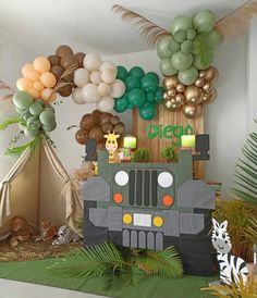 a party setup with balloons, decorations and an army truck on the ground in front of a jungle theme