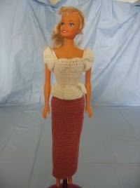 a barbie doll wearing a red skirt and white top with crochet on it