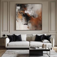 an abstract painting hangs above a white couch in a neutral living room with black and gold accents